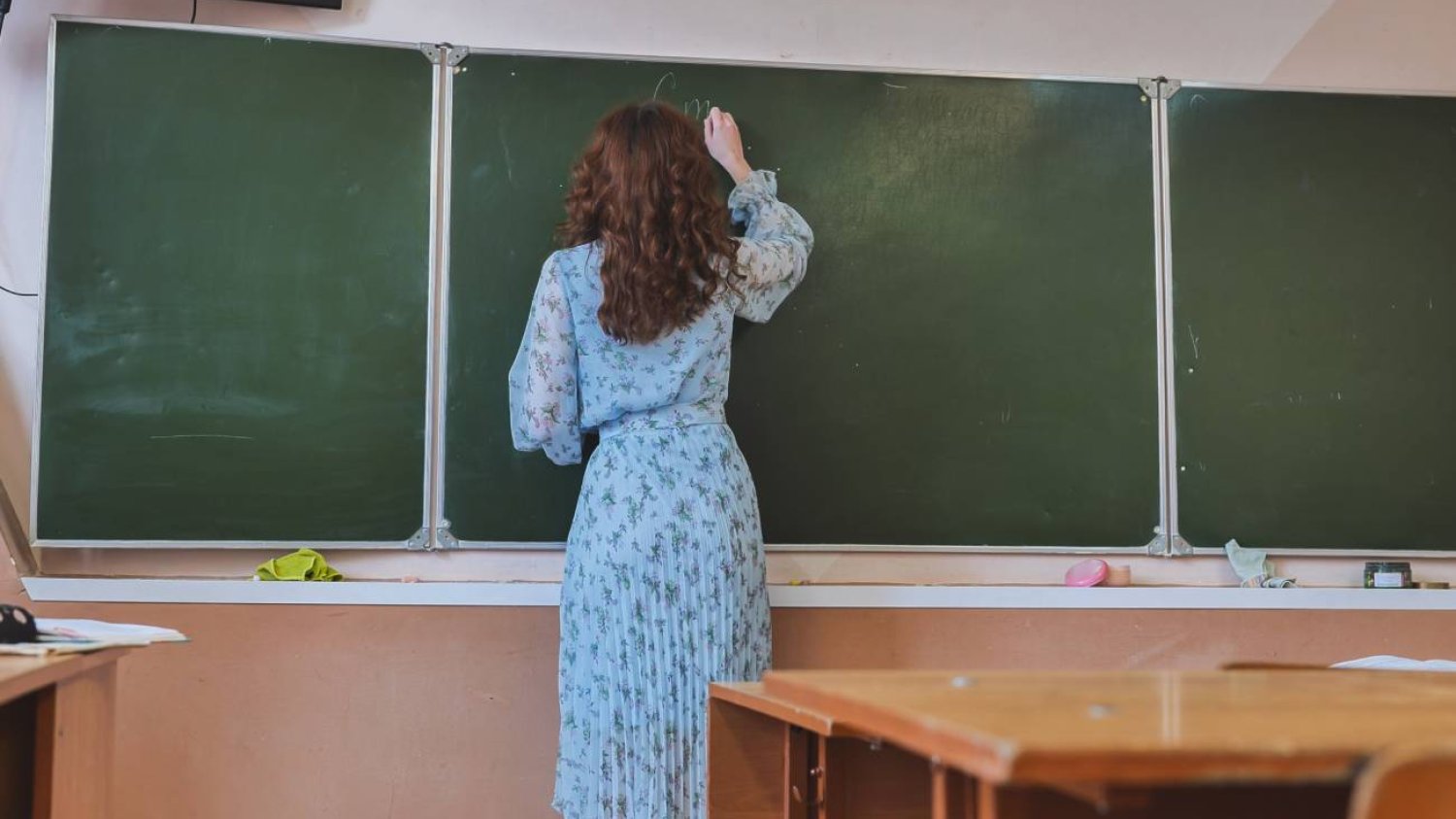 Nauczycielka pisze na tablicy w klasie. Nauczycielka pisze na tablicy w klasie.