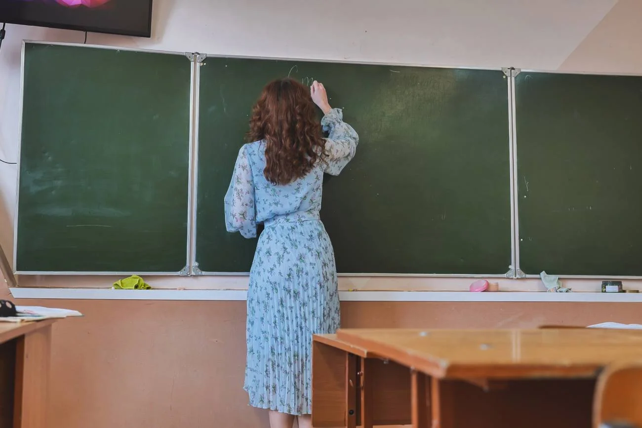 Nauczycielka pisze na tablicy w klasie. Nauczycielka pisze na tablicy w klasie.