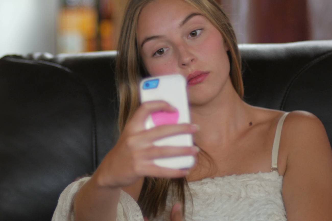 młoda kobieta patrzy w ekran telefonu