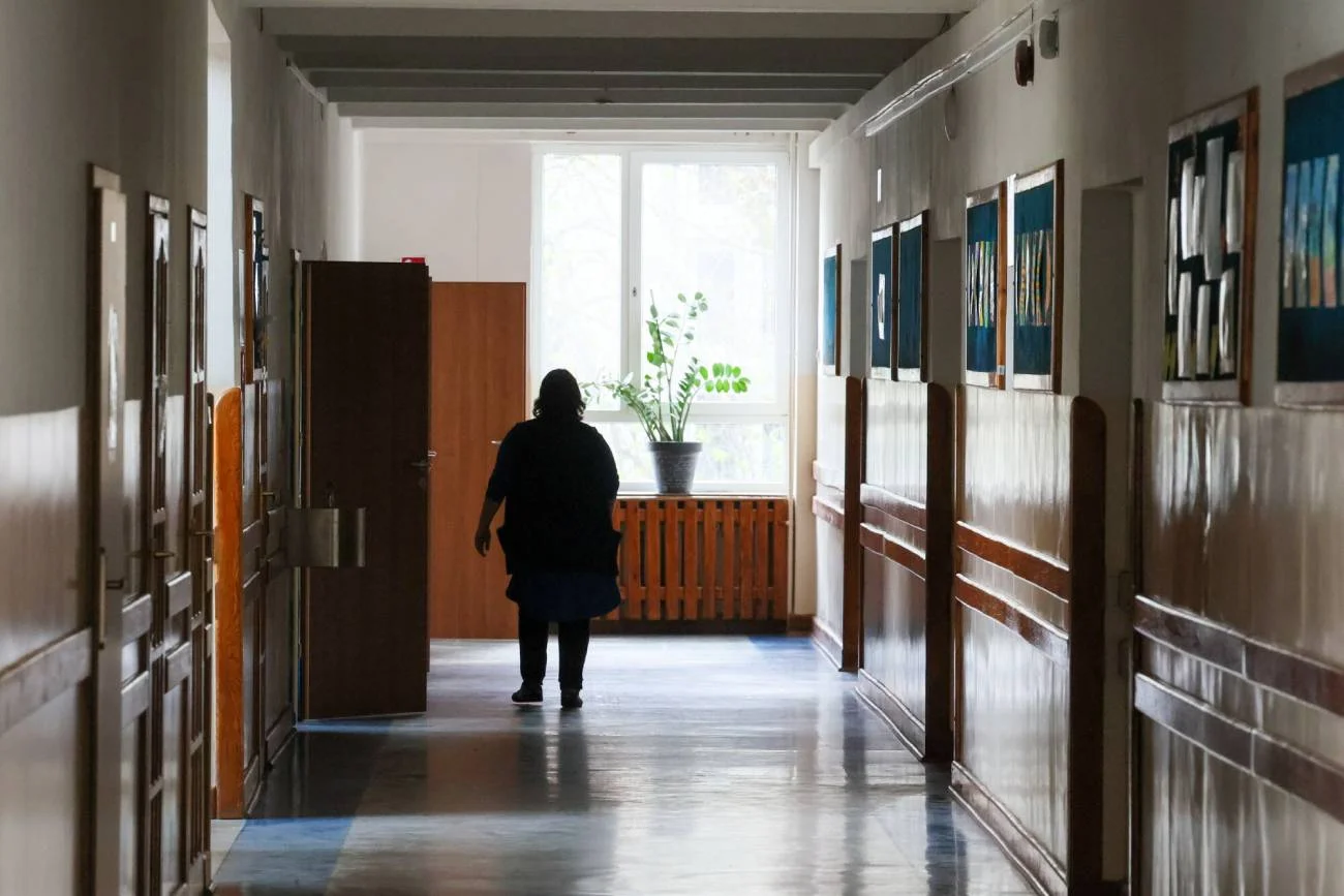 Nauczycielka idąca szkolnym korytarzem.
