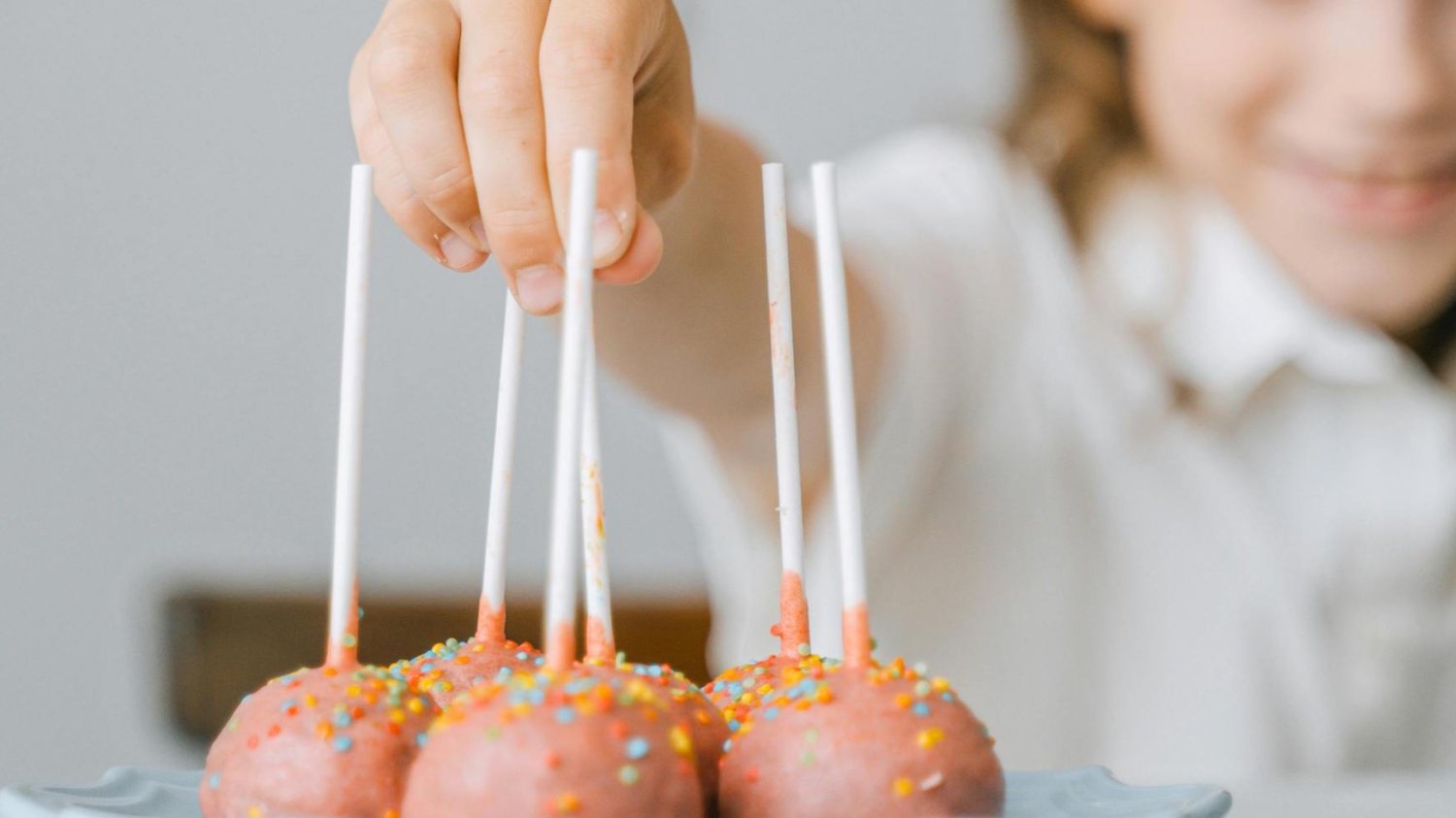Na zdjęciu dziecko sięga po cake popsa.