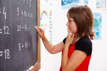 Uczennica rozwiązuje przy tablicy działania matematyczne.