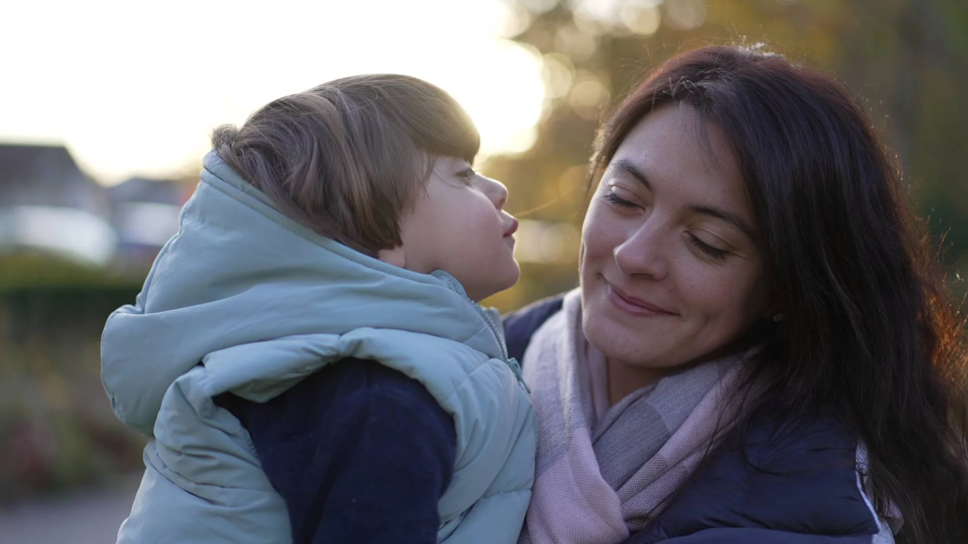 mama z dzieckiem, które chce jej dać buziaka w policzek mama z dzieckiem, które chce jej dać buziaka w policzek