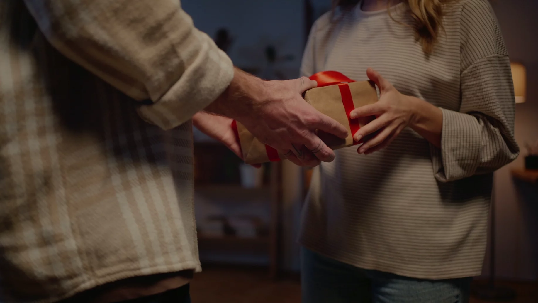 Prezent dla żony Na zdjęciu mąż wręcza żonie prezent.