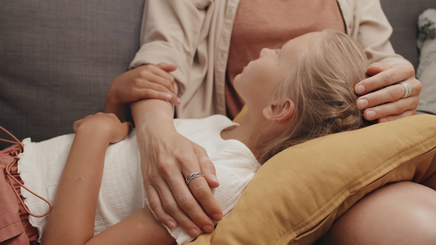 Rozmowa z córką – jakich zwrotów używać Na zdjęciu jest mama z dziewczynką. Córka opiera głowę o kolana mamy i słucha co ona do niej mówi.
