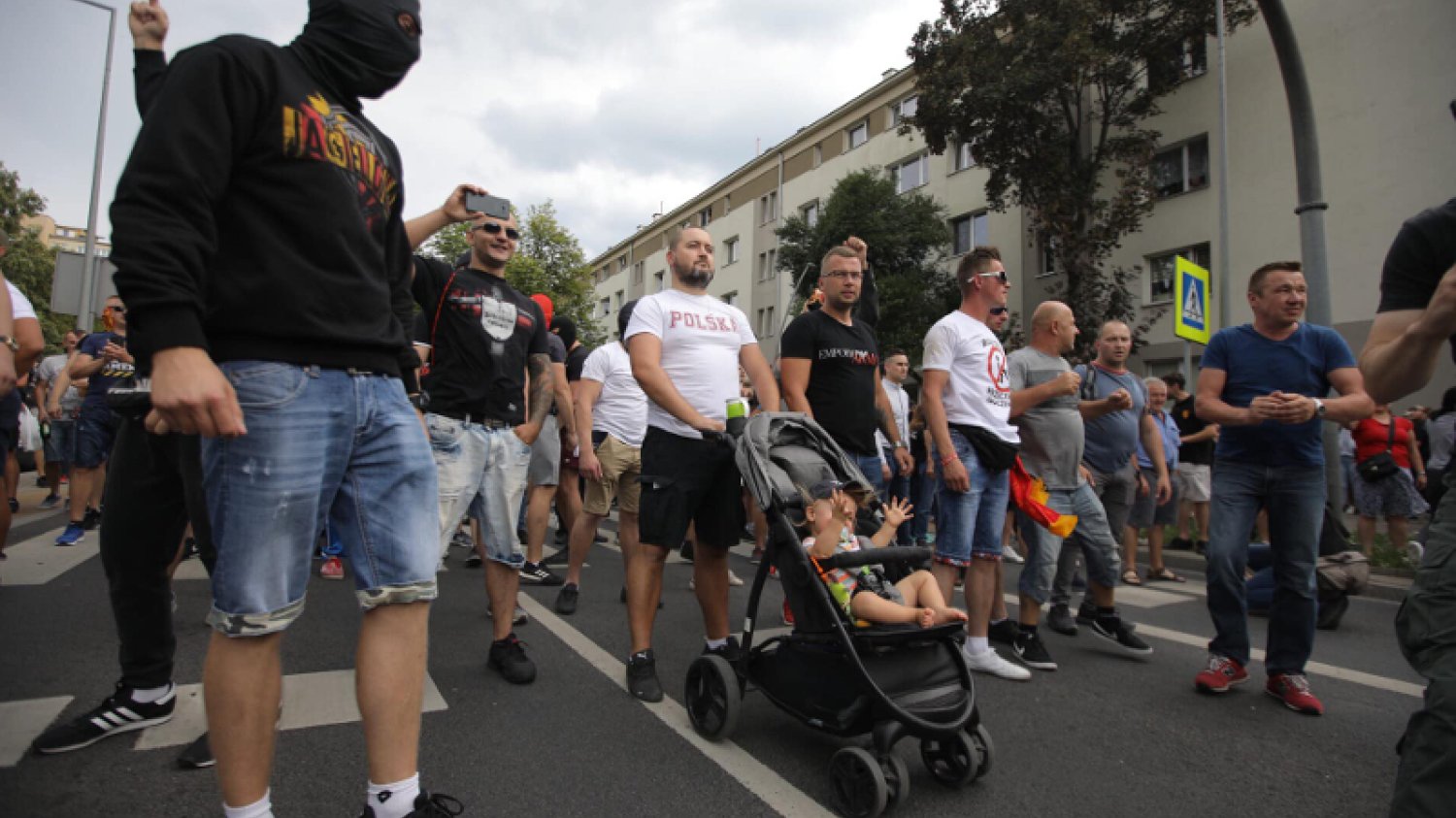 Dziecko jako żywa tarcza swojego ojca. Obok mężczyzna w kominiarce