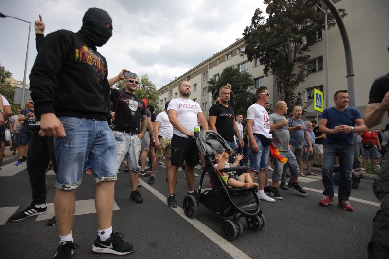 Dziecko jako żywa tarcza swojego ojca. Obok mężczyzna w kominiarce