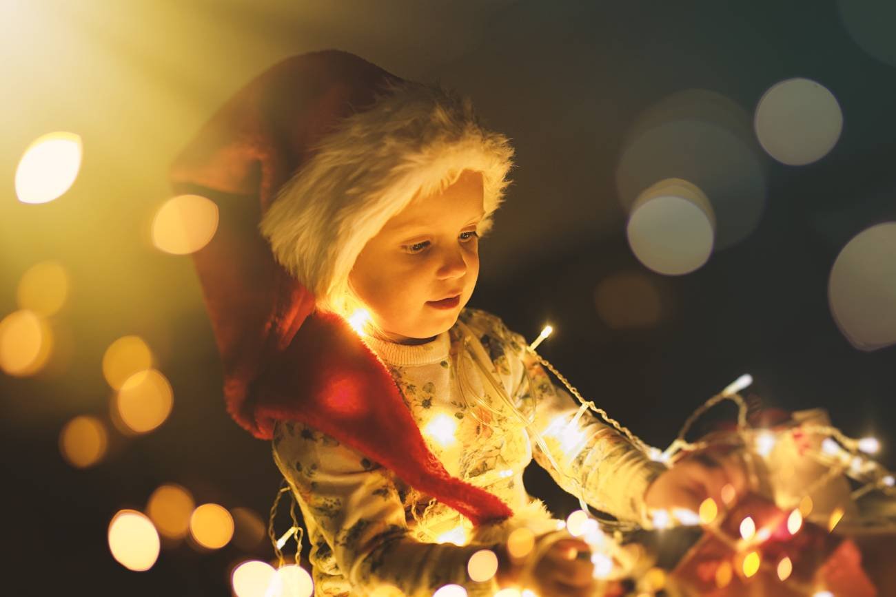 Dziecko w czapce mikołaja z lampkami choinkowymi. Dziecko w czapce mikołaja z lampkami choinkowymi.