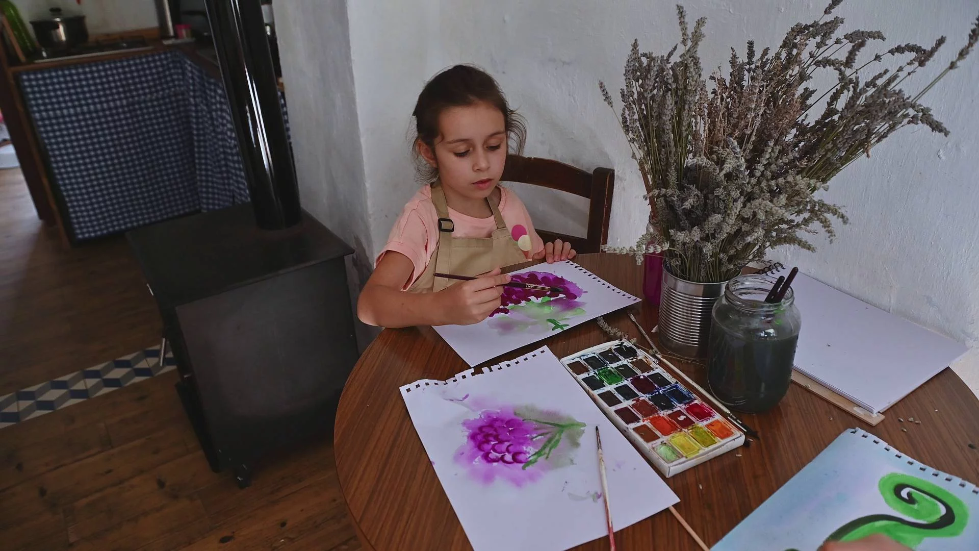 Dziewczynka maluje farbami przy stole