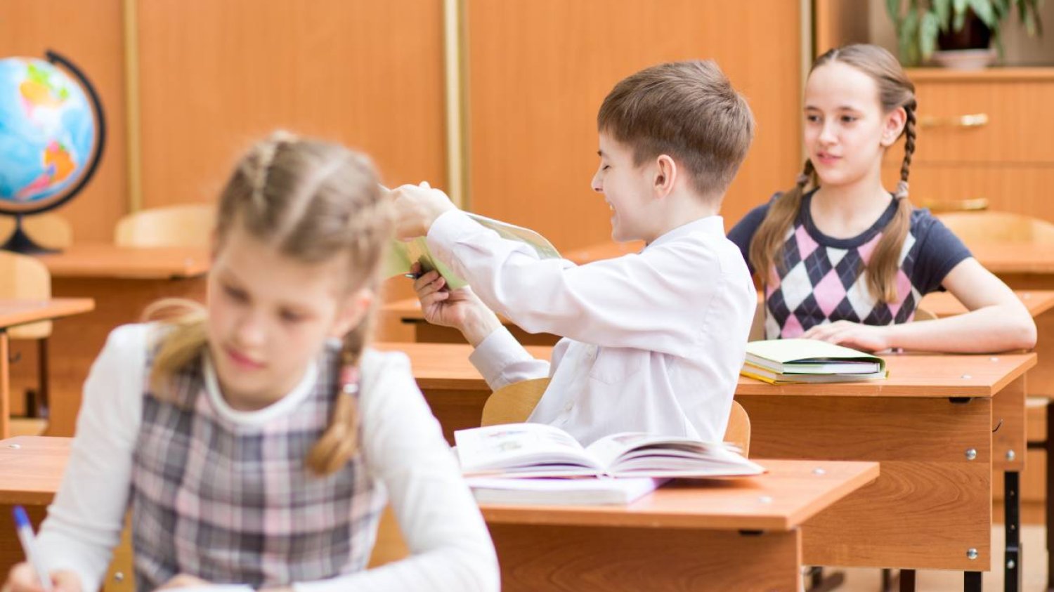 Uczniowie podczas lekcji siedzą w ławkach.