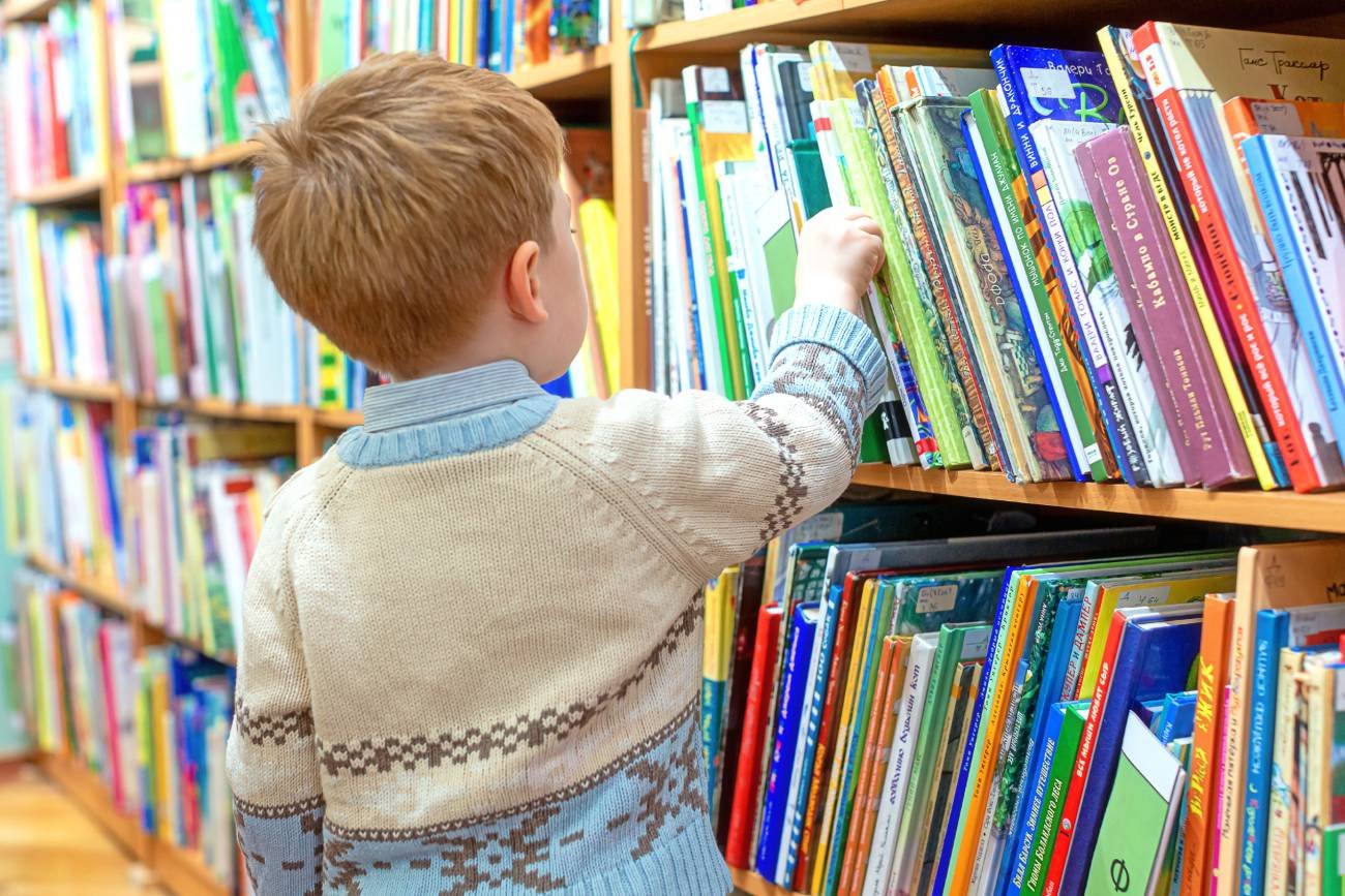 Uczeń wybiera książki w bibliotece.