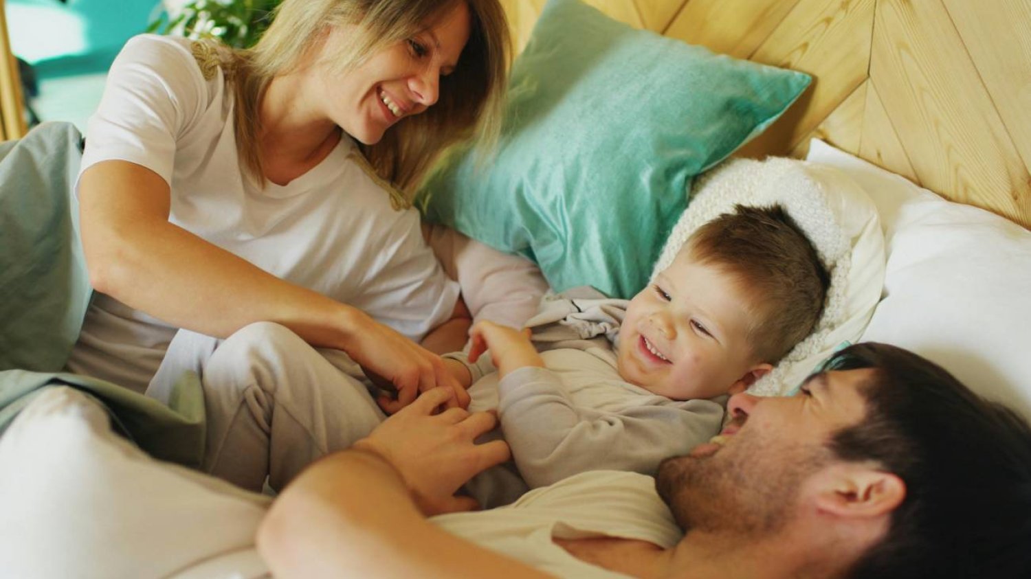 mama i tata bawią się z dzieckiem w łóżku
