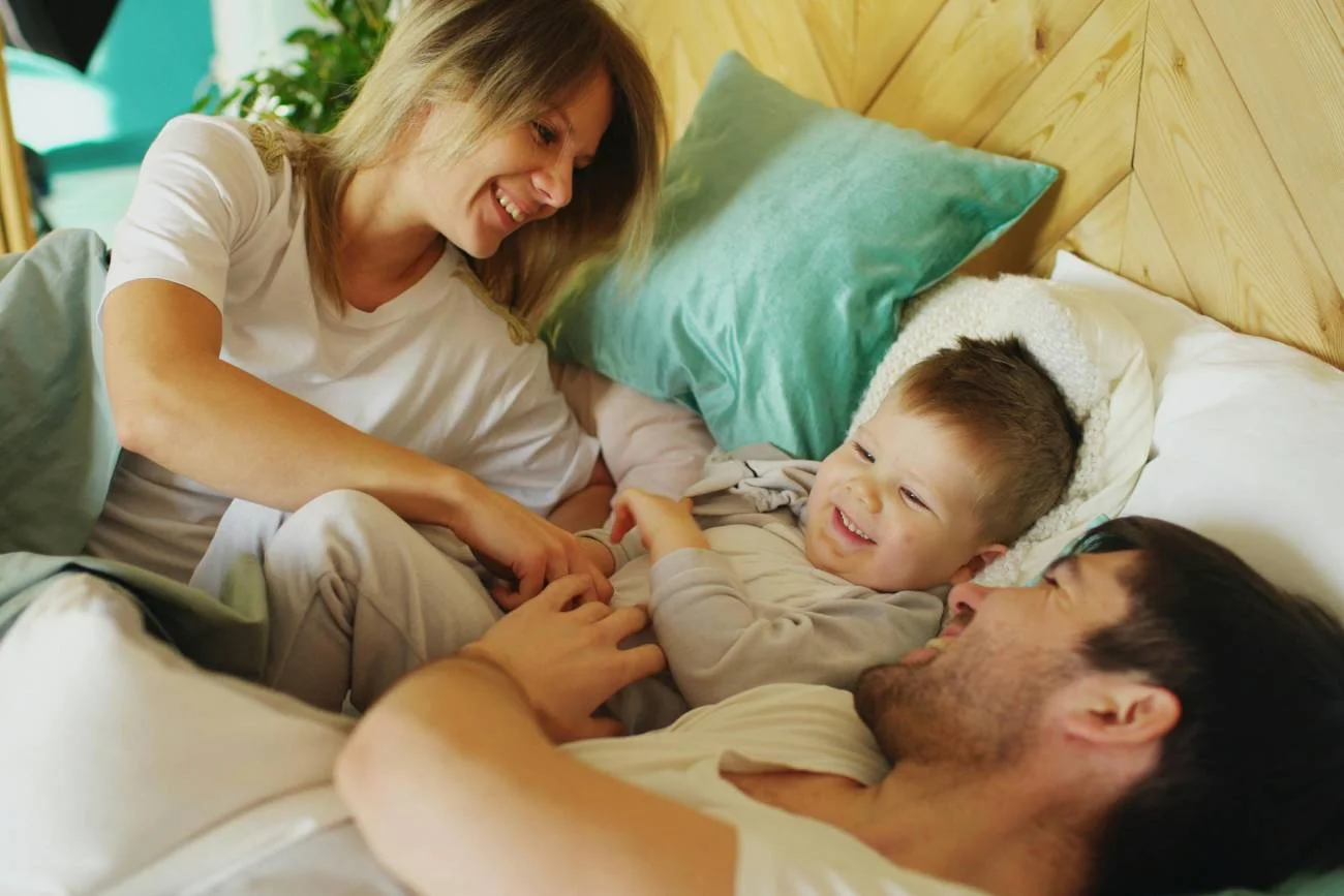 mama i tata bawią się z dzieckiem w łóżku mama i tata bawią się z dzieckiem w łóżku