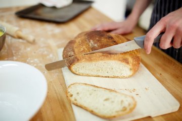 młoda dziewczyna krojąca bochenek chleba młoda dziewczyna krojąca bochenek chleba