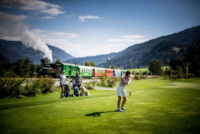 Styria przyciąga również miłośników golfa. W tle ciuchcia Murlabahn.