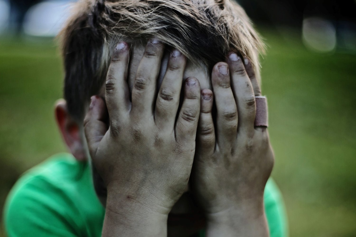 Chłopiec płacze, brudne ręce, zasłania twarz.