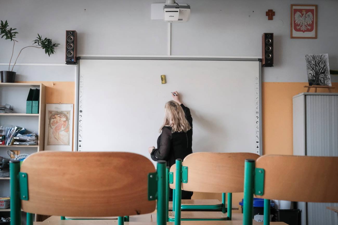 nauczycielka w klasie pisze na tablicy