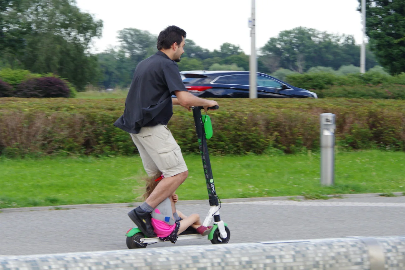tata wiezie córkę na hulajnodze elektrycznej