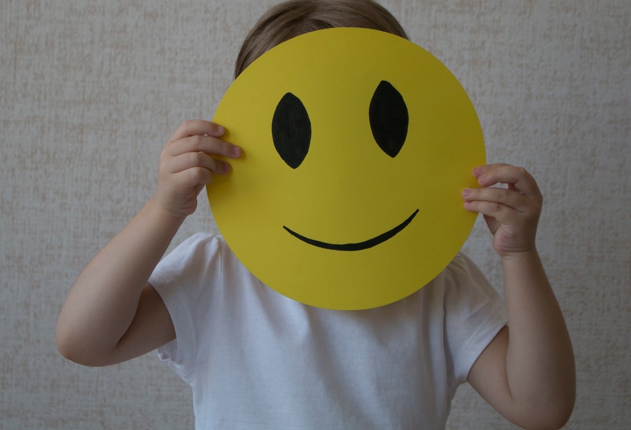 dziecko zasłania twarz emotką