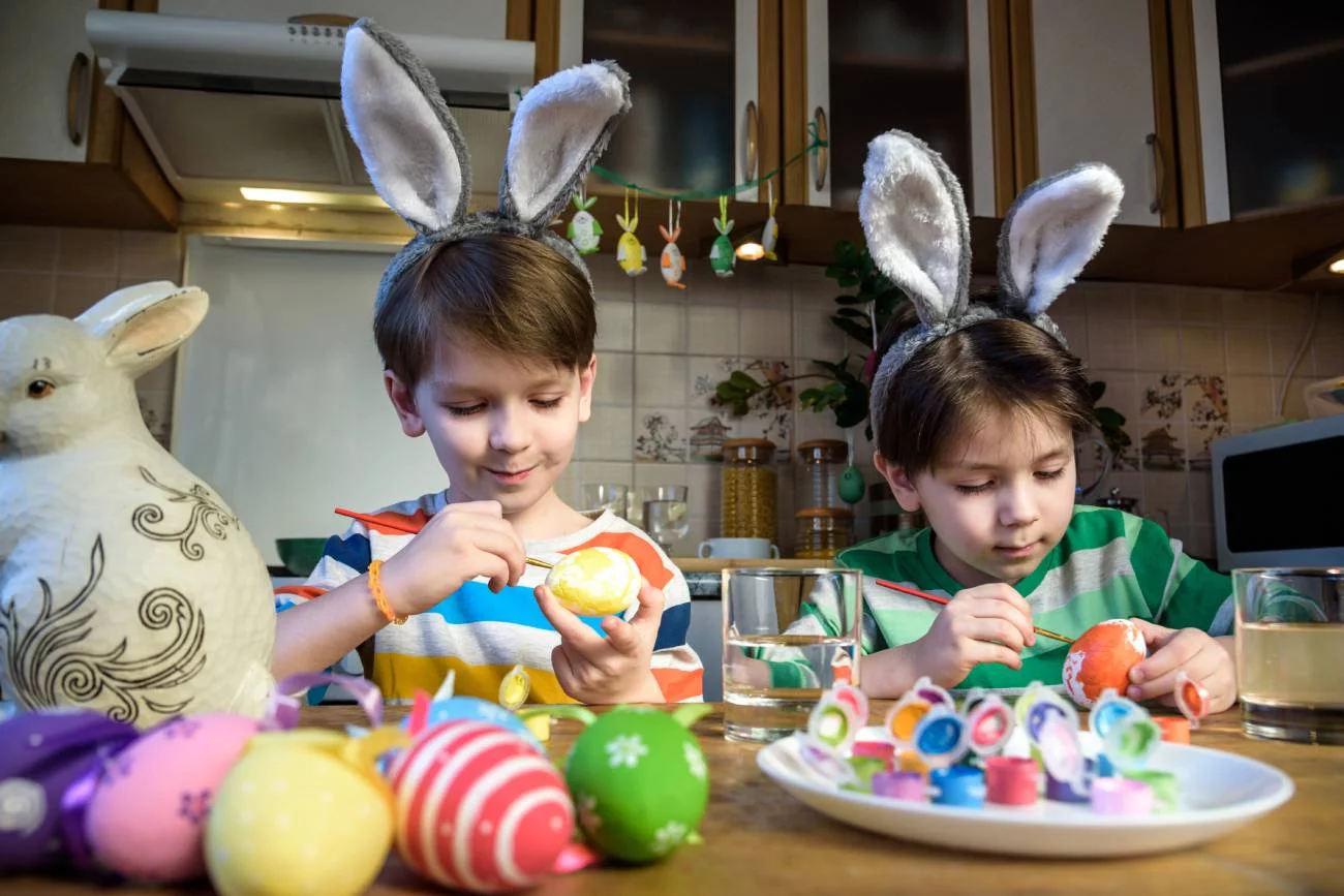 Kilkulatki malują pisanki przy kuchennym stole.