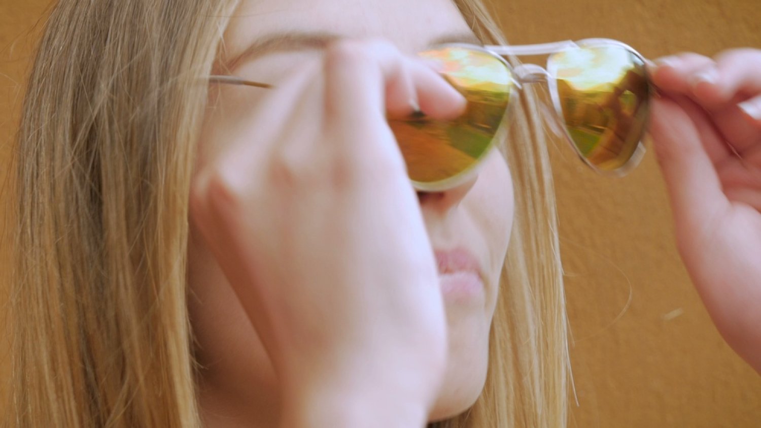Na zdjęciu widać kobietę zakładającą okulary pilotki