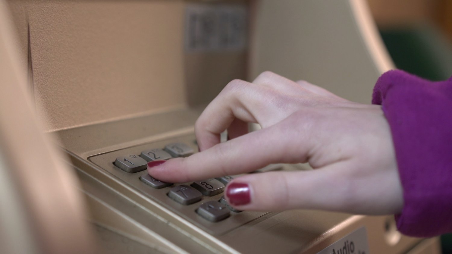 Na zdjęciu kobieta wypłaca coś z bankomatu