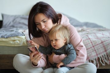 mama z niemowlakiem patrzy w telefon
