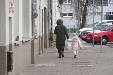 Kobieta idzie przez miasto z małym dzieckiem. Kobieta idzie przez miasto z małym dzieckiem.