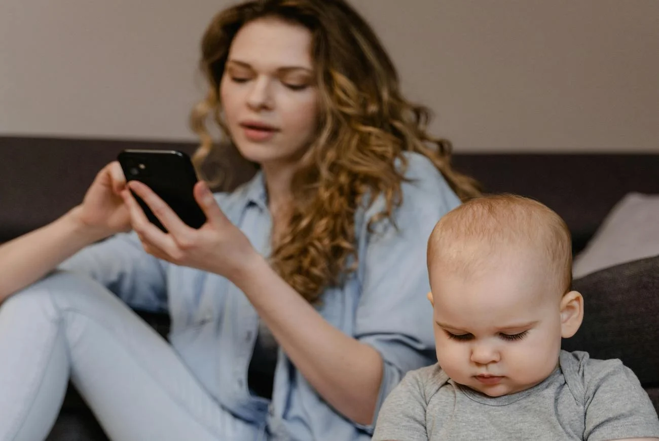 mama scrolluje telefon przydziecku