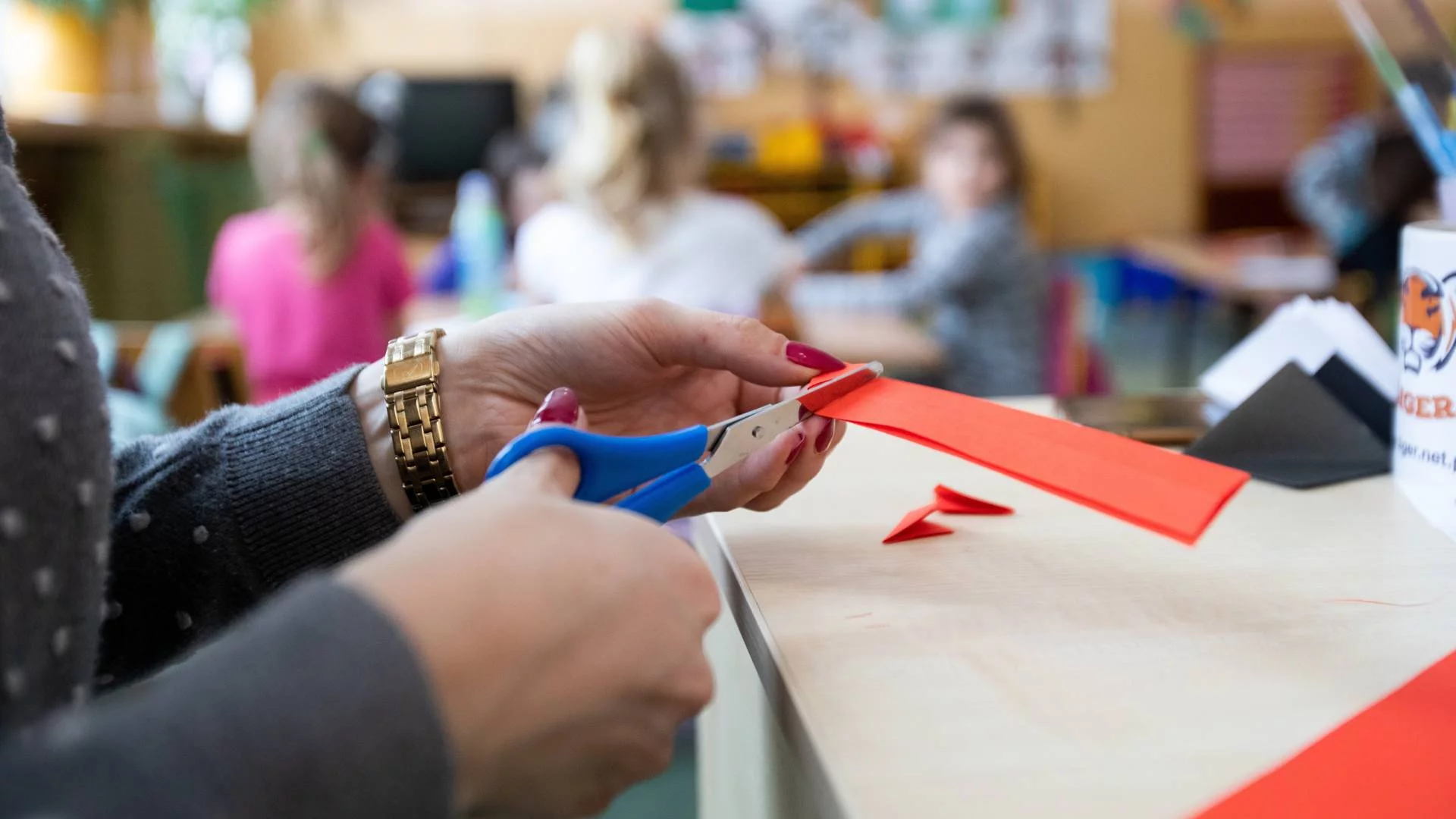 nauczycielka przedszkolna wycina ozdoby z papieru na przedszkolne święto
