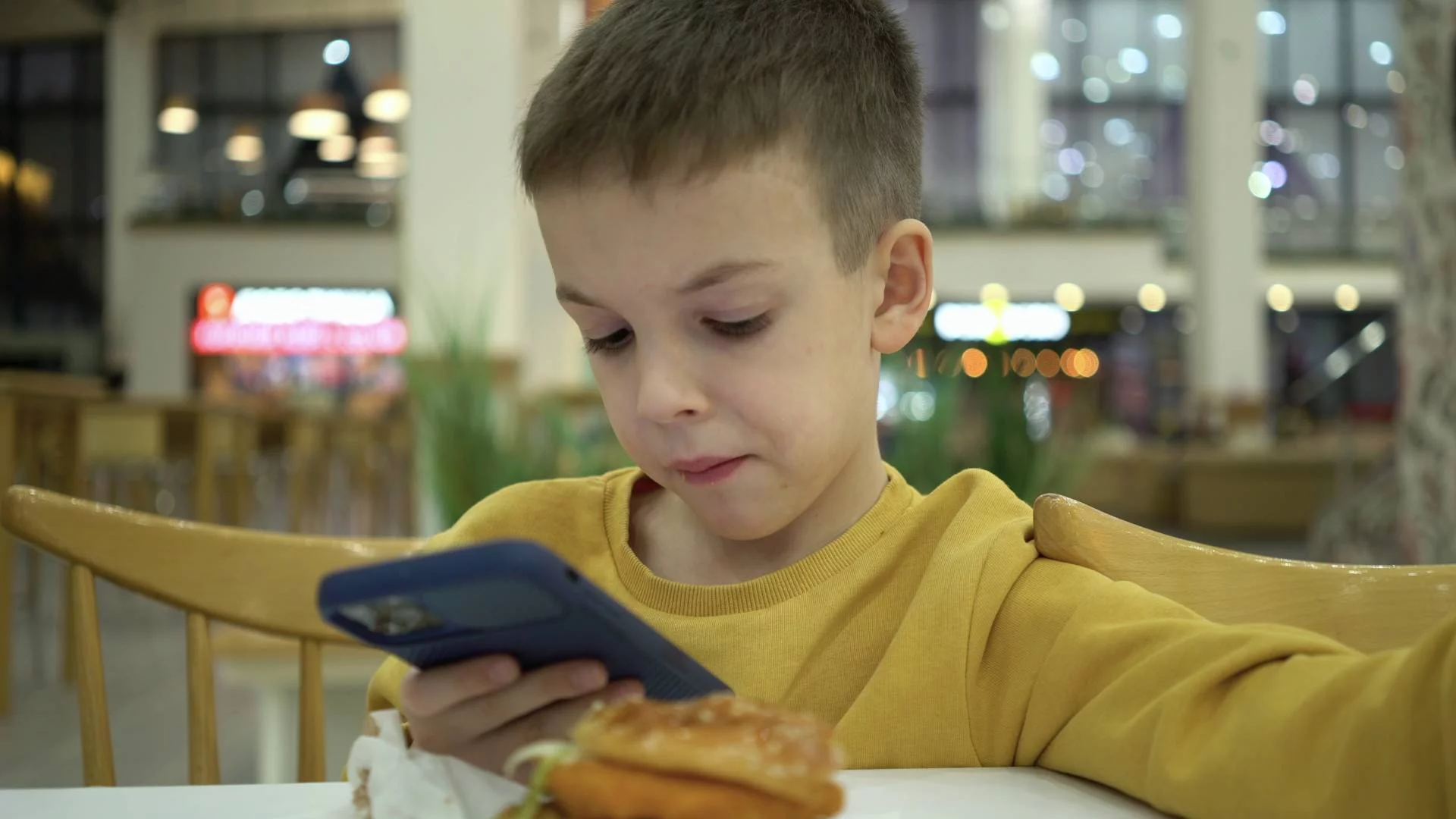 9-letni chłopiec patrzy w ekran smartfona