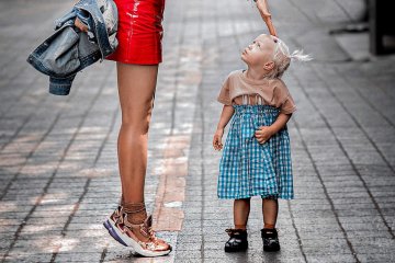 Mała dziewczynka stoi na chodniku z dorosłą kobietą