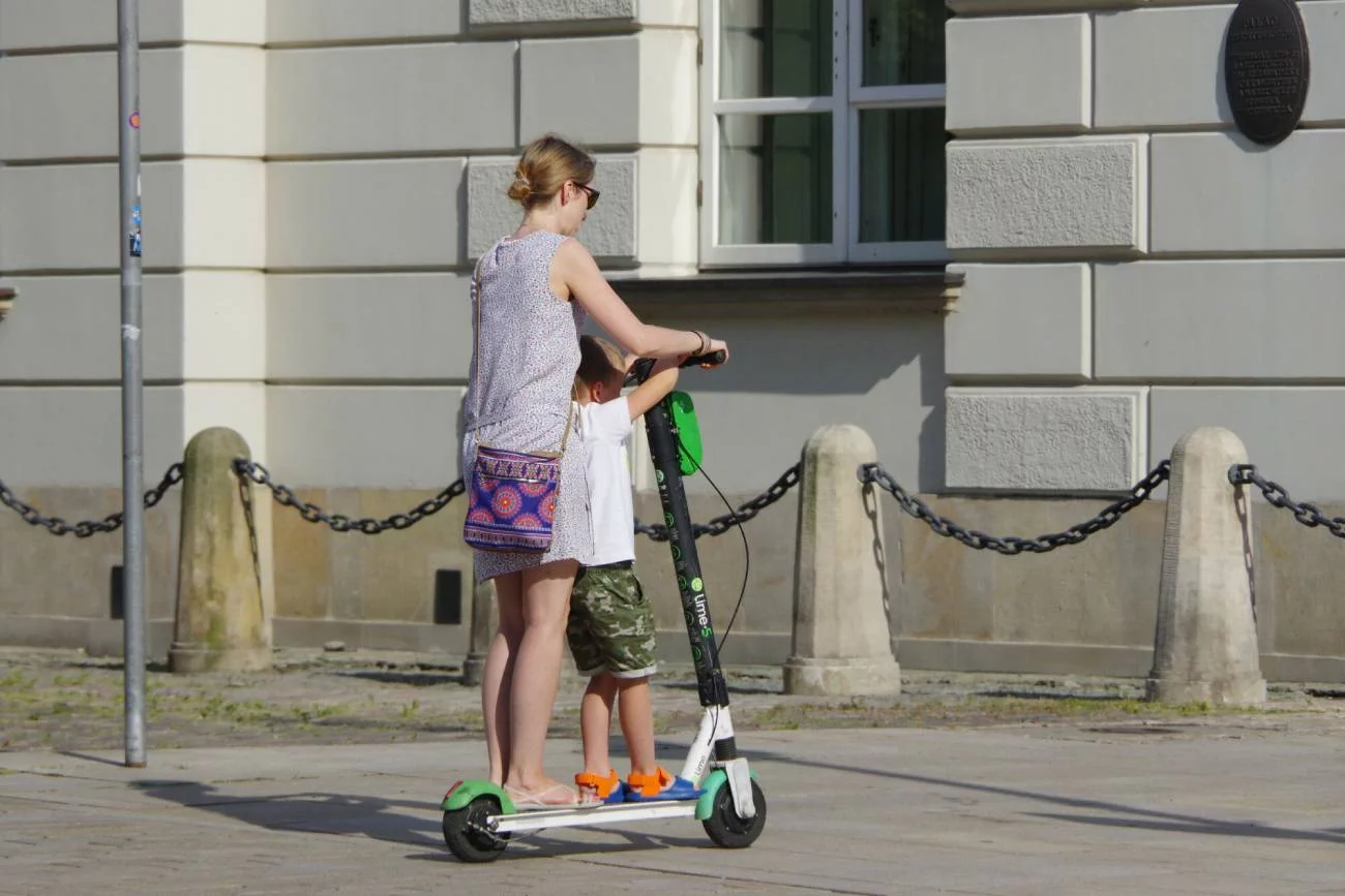 Matka jedzie na elektrycznej hulajnodze z dzieckiem. Matka jedzie na elektrycznej hulajnodze z dzieckiem.