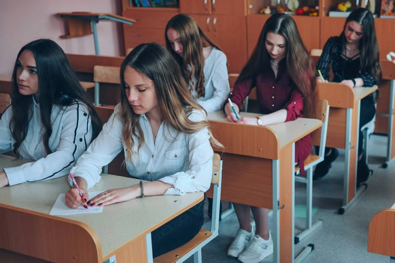 Uczennice siedzą w ławkach na lekcji.