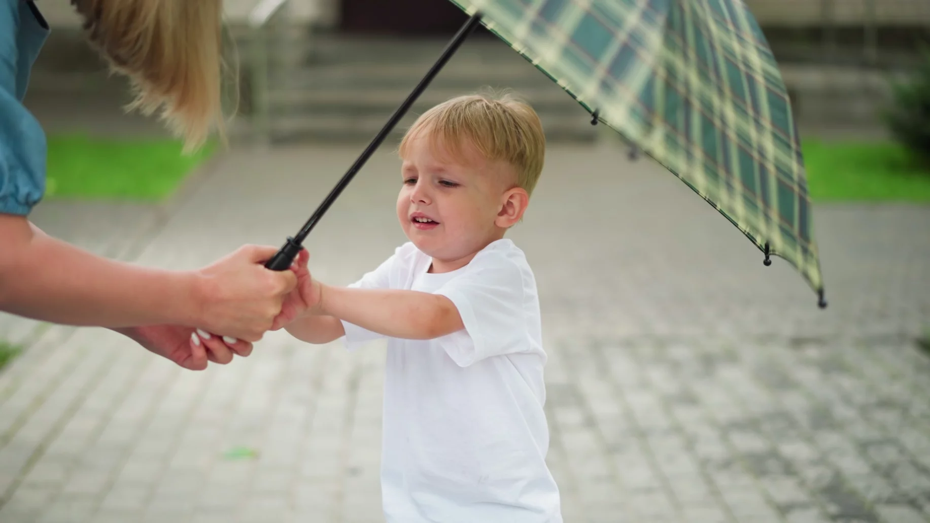 Mama na siłę podaje dziecku parasol, a ono go nie chce