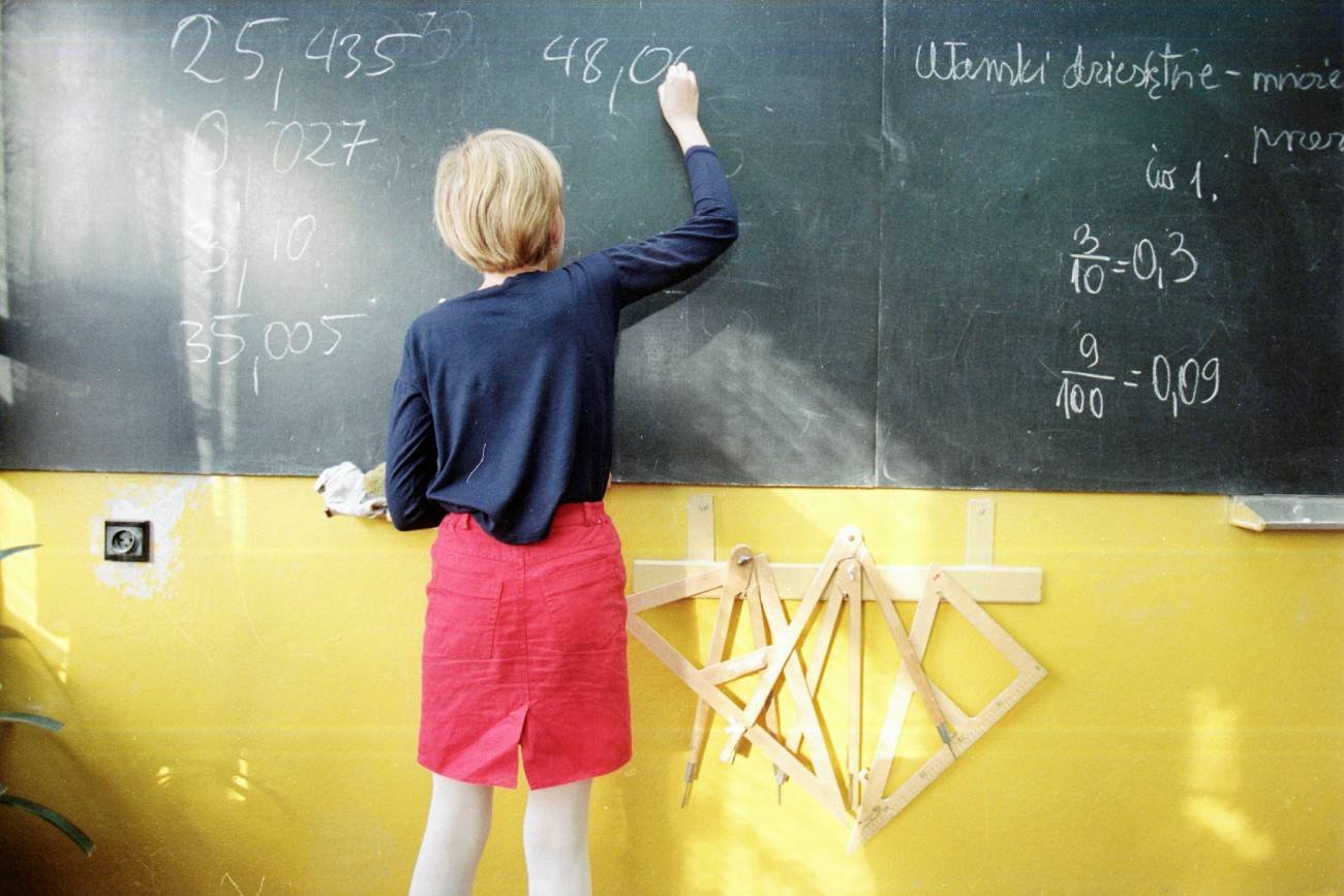 nauczycielka w klasie pisze na tablicy