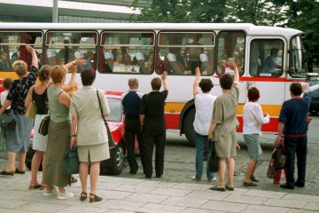 Rodzice żegnają autokar z dziećmi, który jedzie na kolonie.