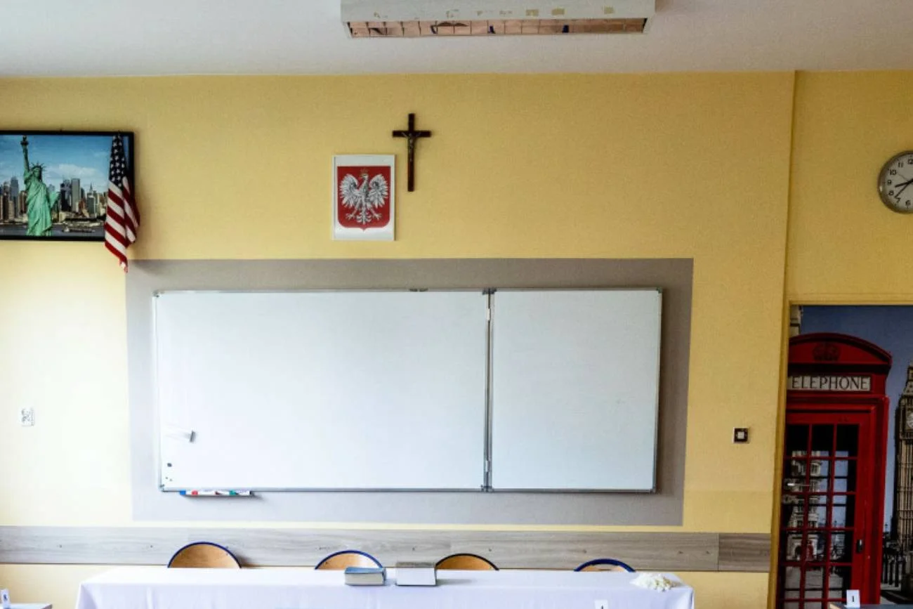 Klasa lekcyjna z krzyżem na ścianie.