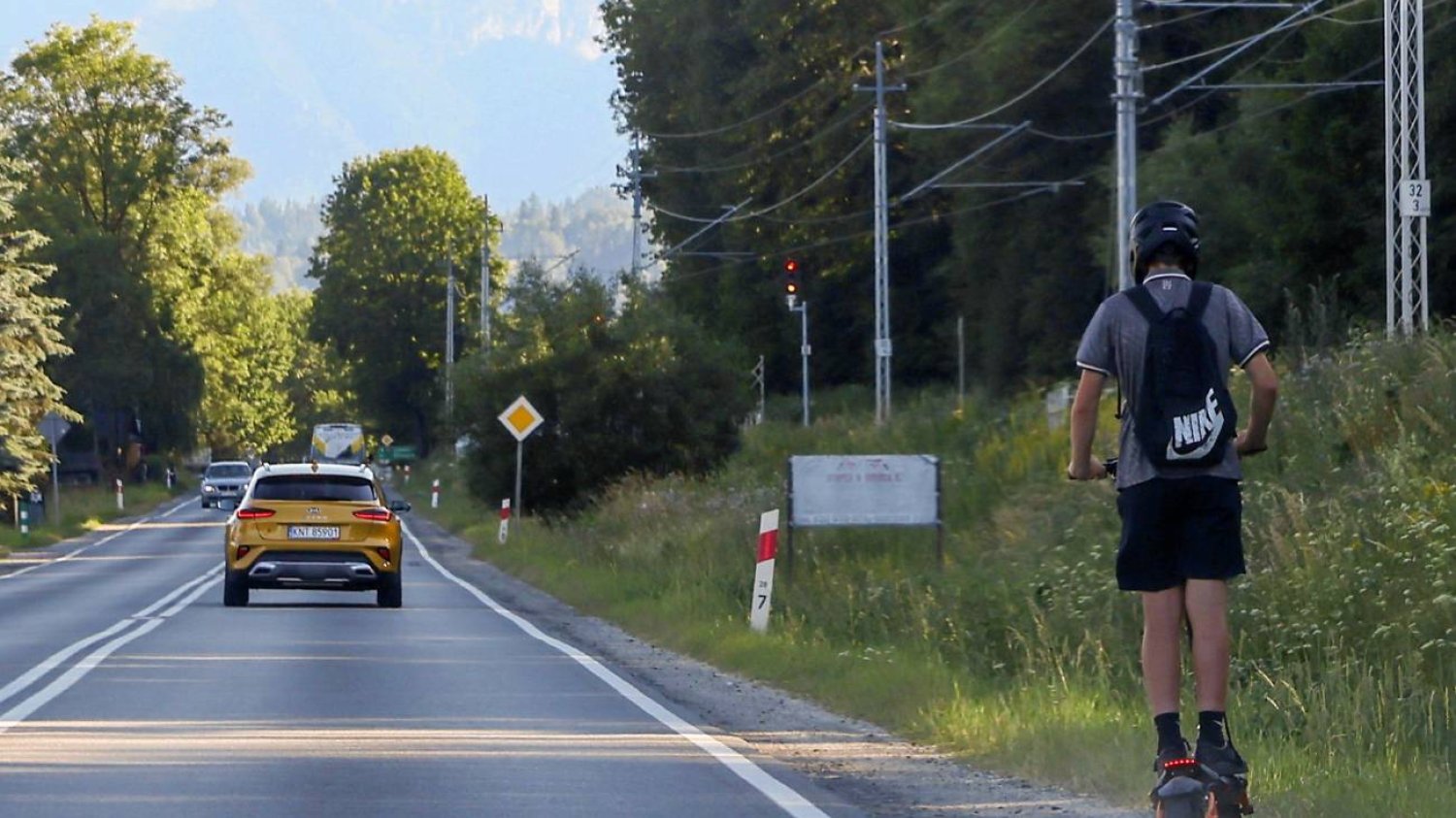 chłopak z plecakiem jedzie hulajnogą elektryczną wzdłuż ulicy chłopak z plecakiem jedzie hulajnogą elektryczną wzdłuż ulicy