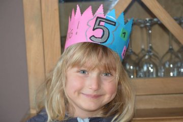 5-letnia dziewczynka świętuje w papierowej koronie swoje urodziny.