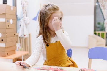 dziewczynka głowi się nad zagadką dla dzieci