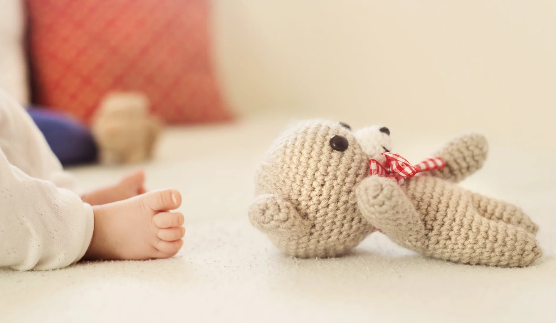 Na zdjęciu widać leżącego misia i stópki noworodka.