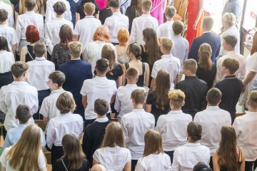 uczniowie w strojach galowych na zakończeniu roku szkolnego