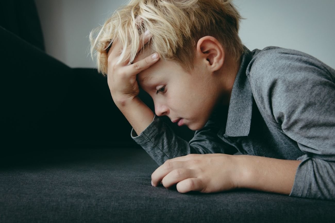 Zmęczone dziecko trzyma się za głowę