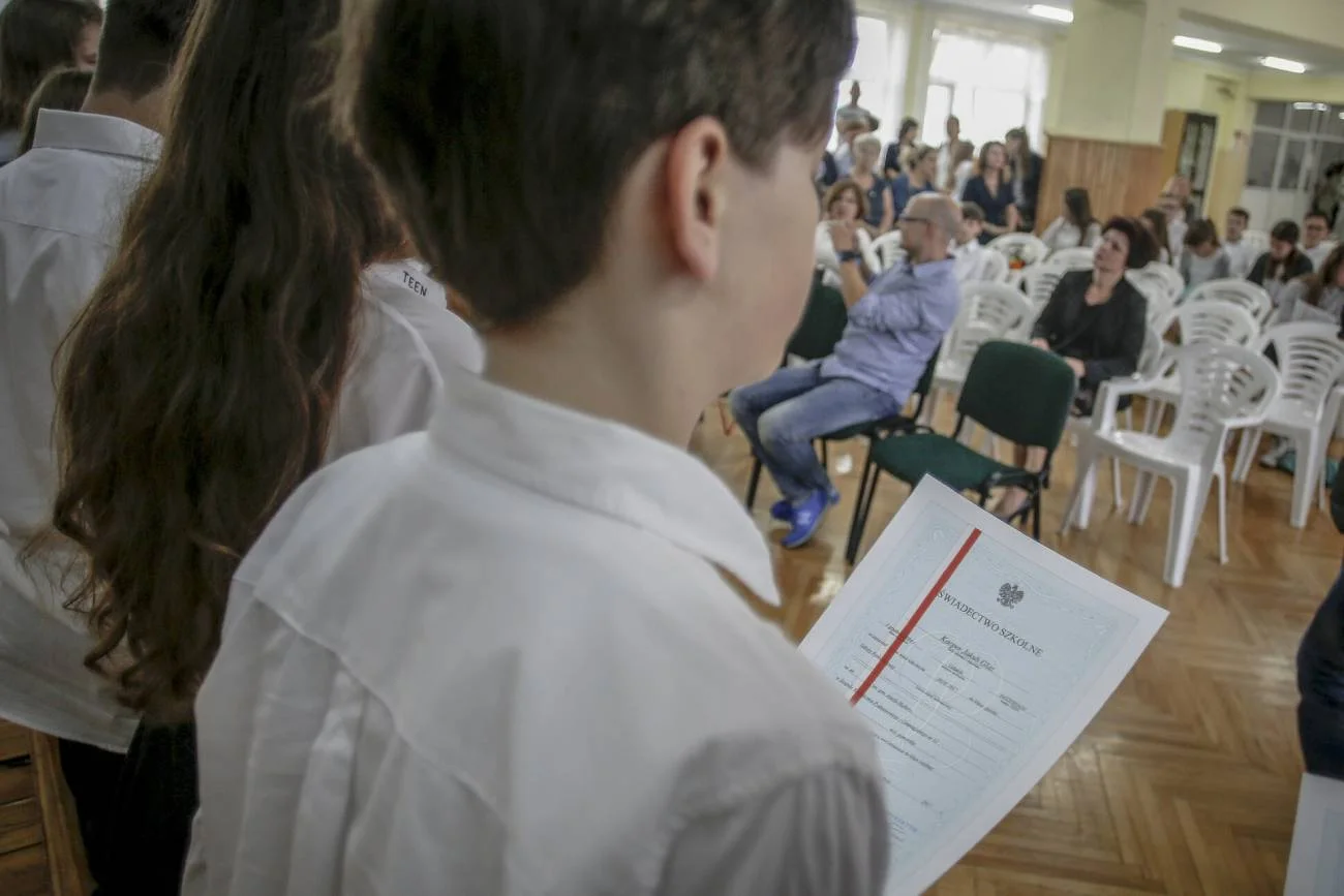 Uczeń odebrał świadectwo z czerwonym paskiem na koniec roku szkolnego.