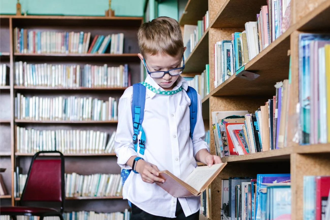 Uczeń powtarza lekcję z podręcznika w szkolnej bibliotece.
