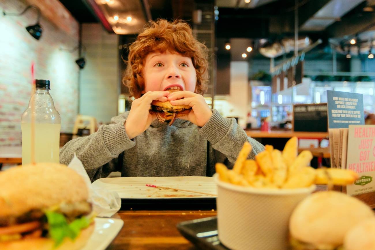 Chłopiec je burgera w McDonald's: kanapkę Drwala.