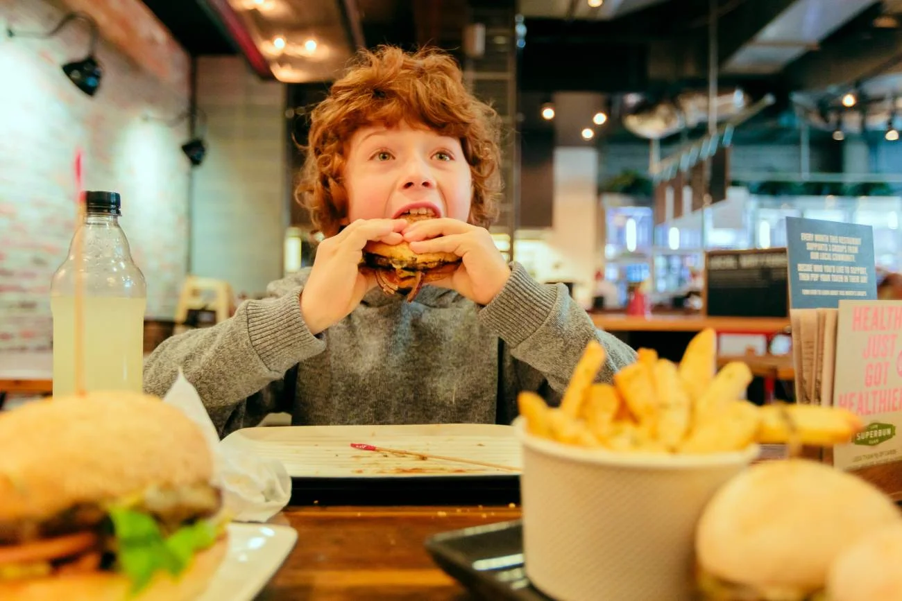 Chłopiec je burgera w McDonald's: kanapkę Drwala.