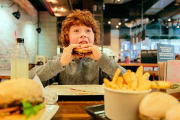 Chłopiec je burgera w McDonald's: kanapkę Drwala.