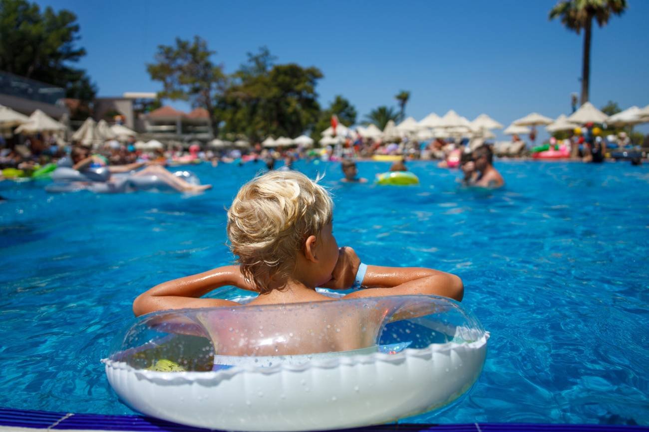 Dziecko kąpie się w basenie na all inclusive.